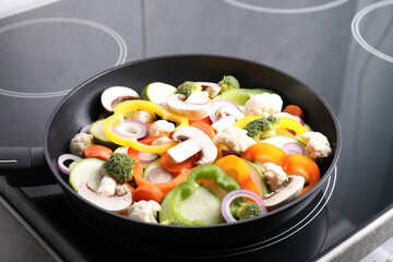 Frying pan with mix of vegetables and mushrooms on cooktop, closeup