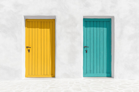 Two colorful doors on a white wall, a yellow and a turquoise one