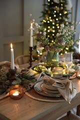 Christmas celebration. Festive table setting with dishware, glasses and decor in room