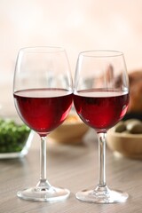 Red wine and delicious dinner served on wooden table, closeup