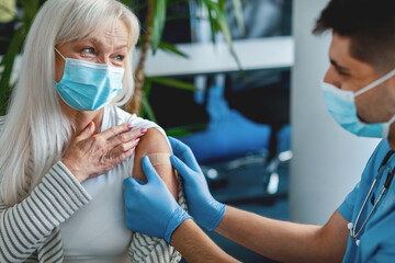 Mature Woman Getting Vaccinated Against flu, Doctor Applying Plaster After Giving Coronavirus...