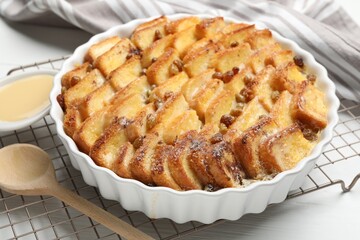 Delicious bread pudding with raisins and condensed milk on white table, closeup