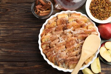 Delicious bread pudding with raisins, cinnamon and apples on wooden table, flat lay. Space for text