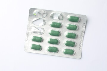 Blister with green pills on white background, top view
