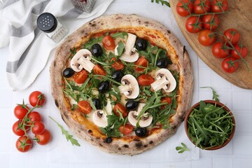 Tasty pizza with cherry tomatoes, black olives, mushrooms and arugula on white tiled table, flat lay