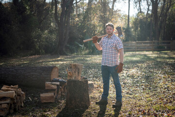 Country homesteading man with ax cutting firewood for campfire or stove in field