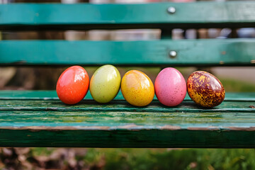 Colorful Easter eggs arranged on a green park bench celebrating spring holiday traditions and festiv