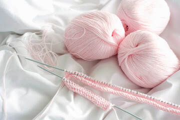 Pink yarn and knitting needles on white background top view.