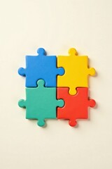 Fototapeta premium A vibrant quartet of interlocking puzzle pieces, symbolizing unity, collaboration, and the synergistic power of teamwork, displayed against a neutral backdrop
