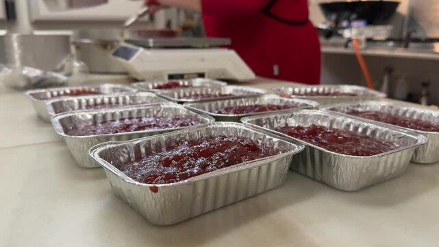A pasrty chef&rsquo;s hands wearing a red apron preparing traditional homemade quince jelly in her artisan bakery.