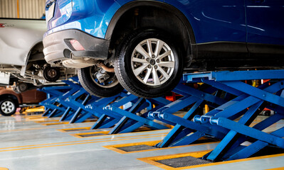 Car suspension maintenance during tire replacement at a garage workshop with professional mechanic...