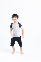 A happy Thai boy with messy hair laughs playfully while standing barefoot against a white background.