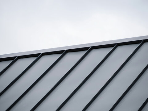 Modern Tray Metal Roof and Black Standing Seam Panels Against Cloudy Sky