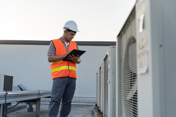 Asian maintenance engineer works on the roof of factory. contractor inspect compressor system and...