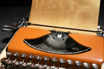 Vintage typewriter with parchment paper on black background, closeup