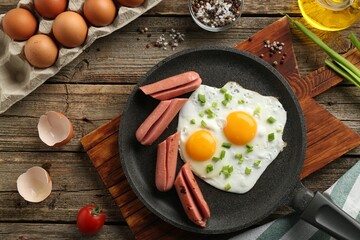 Tasty fried eggs with cut sausages served on wooden table, flat lay