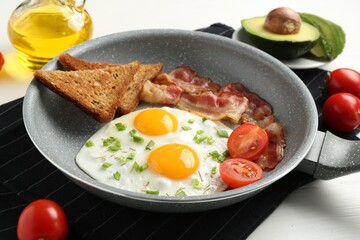 Tasty fried eggs with bacon and toasts served on white wooden table, closeup