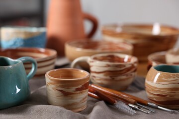 Different beautiful pottery and set of clay crafting tools on table indoors, closeup