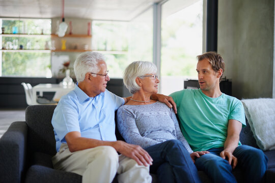 Sofa, old people and son with hug for talking, connection and bonding together with love at home. House, mother and father with adult child for care, conversation and relationship of family on couch
