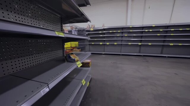 A nearly empty supermarket with bare shelves and minimal stock, symbolizing supply chain issues, panic buying, or economic crisis.