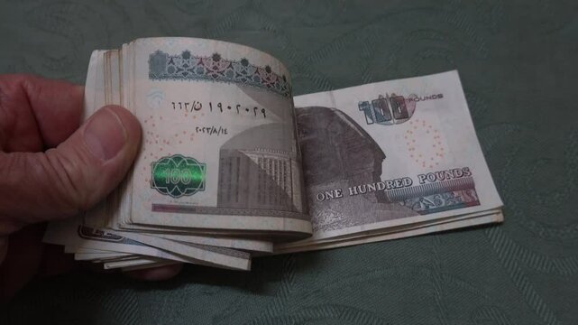 Cairo, Egypt A hand handles a large stack of Egyptian100 pound notes.  