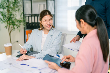 Two professionals engage in a discussion at a modern workspace, surrounded by papers and a coffee cup, showcasing collaboration and teamwork.