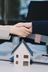 Real Estate or Insurance agent or lawyer shaking hands with couple. They are signing home loan mortgage or contract documents.