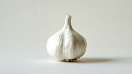 Close-up of one garlic clove with detailed papery skin and light reflecting off its surface, placed on a minimalist white backdrop