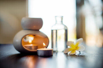 Spa, wellness candles and essential oil with flower on table for aromatherapy massage, luxury treatment or self care. Hotel, zen salon and empty room with pamper products, stress relief or relaxation