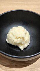 Mashed potatoes in a black cup on a wooden table