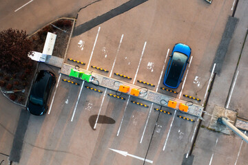 Sustainable power supply for EV is offered by the city street hub, ensuring eco-friendly energy, top view. Charging of blue electric car. 