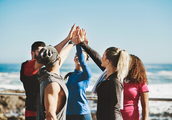 People, fitness and beach with high five for motivation, success or teamwork in nature. Group, friends or community with touch, huddle or unity for solidarity, mission or workout goals by ocean coast