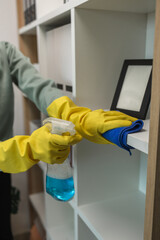 the wife is cleaning her husband home office, cleanup the room, wearing rubber glove to protect her hands, the housekeeper is cleaning the house, tidy up