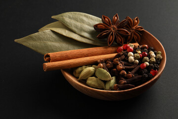 traditional spices. dry cloves, anise stars, cardamom, cinnamon, mixture of peppers and bay leaf in a wooden bowl.