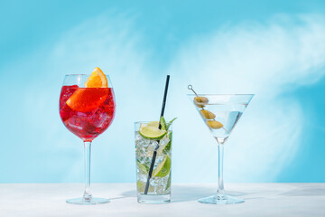 A variety of cocktails arranged on a table against a light blue background