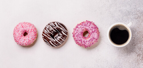 An assortment of vibrant donuts with colorful toppings and a coffee cup