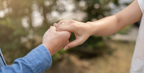 close up man hand touching woman finger with engagement ring at outdoor park in evening to show love and affection for people lifestyle and couple lover concept