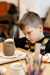 A boy creates a pot and decorating in a pottery workshop © Elina Leonova