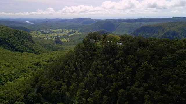 A breathtaking aerial view from Binna Burra, showcasing the mountains and valleys of the Gold Coast Hinterland with the distant city skyline visible on the horizon.