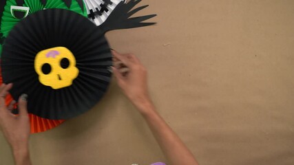 Tabletop shot of artist's delicate hands crafting Halloween paper rosettes - Powered by Adobe