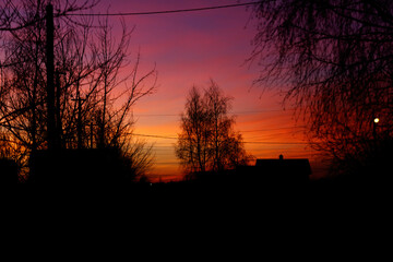 A beautiful sunset over a forest with a house in the background