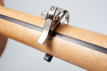 Six-string electric guitar, with a cream-colored wooden body, chrome fittings and capo.