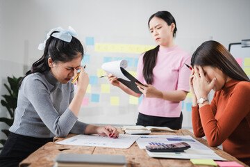 Fototapeta premium Asian people, frustrated businesswoman sits at desk, grappling with challenges of her startup, acknowledging failure, and seeking ways to learn and grow. team meeting. blamed