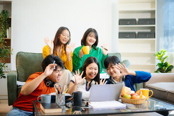 Group of young adults in casual wear, using laptops and headphones, enjoying teamwork,