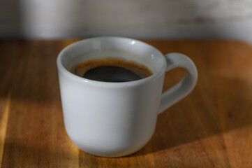 Cozy morning ritual of sipping a rich cup of coffee in soft natural light on a wooden table