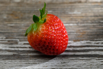 Fresh strawberry resting on a rustic wooden surface, showcasing its vibrant color and natural texture