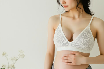 Obraz premium Pregnant Asian Woman in Lace Bra Holding Belly in Minimalist Setting