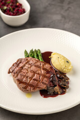 Grilled beef steak with red wine sauce, mashed potatoes, and asparagus