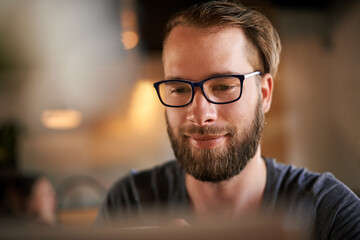 Obraz premium Business, laptop and man in coffee shop, glasses and online reading for email, feedback and report. Person, copywriting and freelancer in cafe, eyewear and internet with pc and review article
