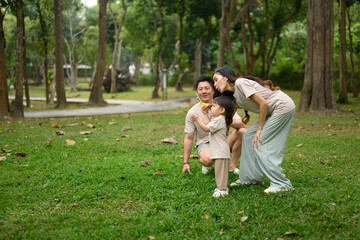 Fototapeta premium Cheerful family enjoys a relaxing day and blowing bubbles in a green park
